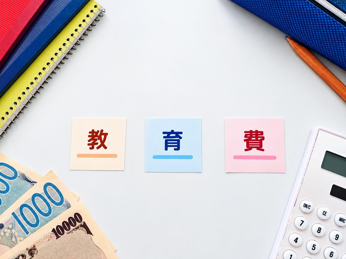 「教育費」と書かれたメモと現金と電卓